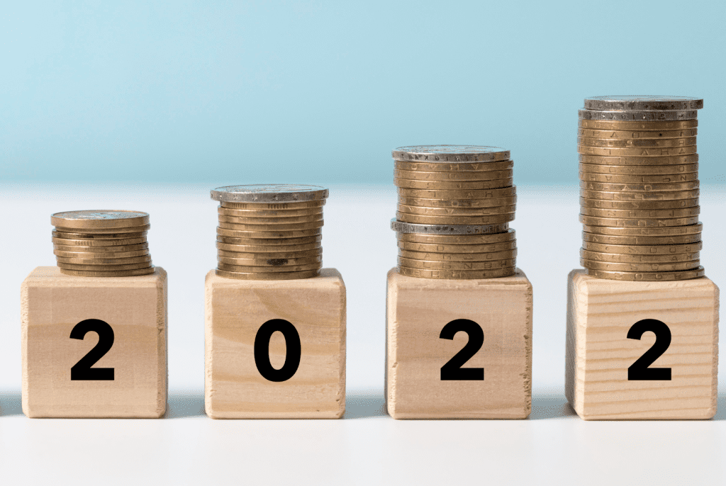 Zdjęcie jest ilustracją artykułu: Rosnąca presja płacowa w firmach – co na ten sądzą temat ekonomiści?
Przedstawia drewniane kostki z cyframi 2022 a na nich stosy monet.