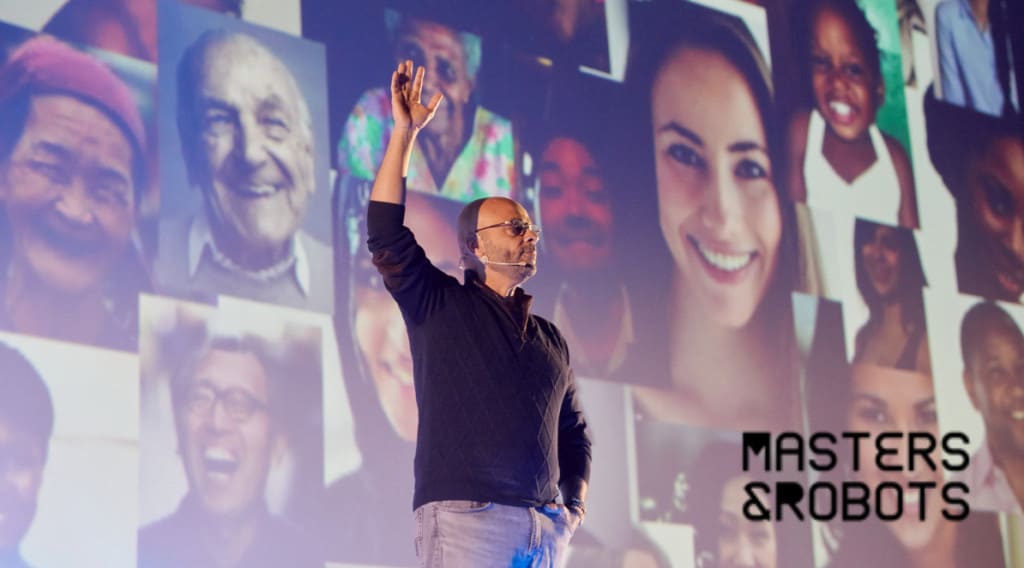 Zdjęcie przedstawia prelegenta Seth Godina na scenie i tle ze zdjęć z twarzami ludzi w różnym wieku i różnej płci. W dolnym prawym rogu logo Masters&Robots