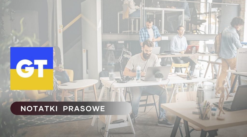 Zdjęcie przedstawia nowoczesne biuro z pracownikami pracującymi przy biurkach. Po lewej stronie znajduje się logo GT na tle ukraińskiej flagi a poniżej nazwa działu: Notatki Prasowe.