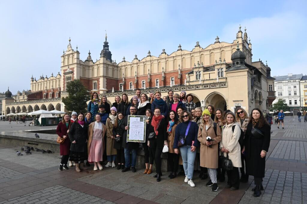 Zdjęcie przedstawia grupę uczestników programu "Biznes kontra smog - Wspieramy klimat", na tle Sukiennic.