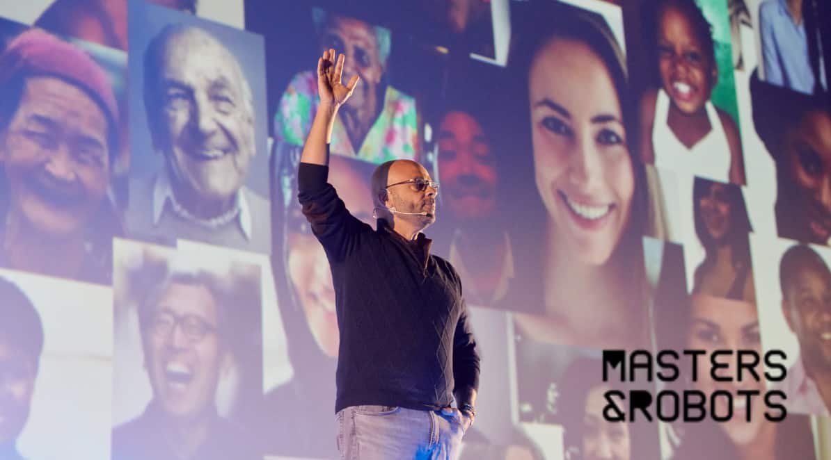 Zdjęcie przedstawia prelegenta Seth Godina na scenie i tle ze zdjęć z twarzami ludzi w różnym wieku i różnej płci. W dolnym prawym rogu logo Masters&Robots