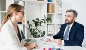 Zdjęcie jest ilustracją do artykułu: Niedojrzałość emocjonalna kierujących ludźmi czyli o marnotrawieniu potencjału. Przedstawia kobietę i mężczyznę rozmawiających w biurze.