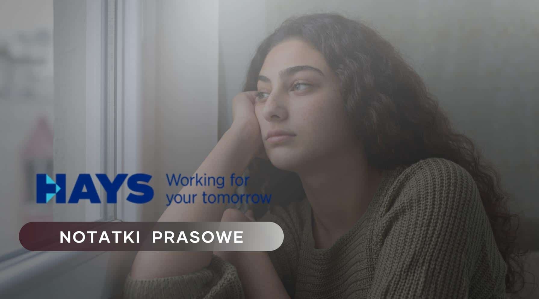 Zdjęcie jest ilustracją do artykułu Młodzi pracownicy, wyzwania edukacyjne i luka kompetencji. Przedstawia młodą kobietę wpatrzoną w widok za oknem. W lewym dolnym rogu znajduje się logo HAYS i tytuł działu: Notatki prasowe.