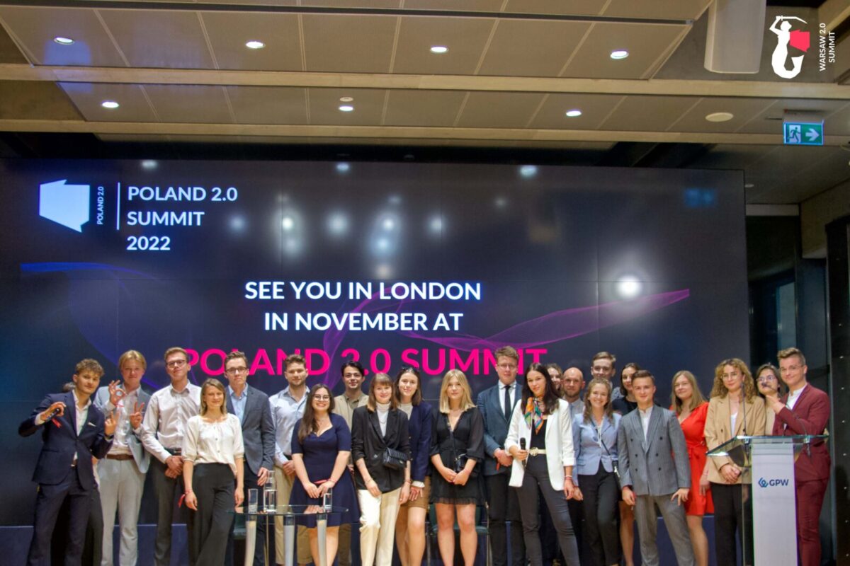 Zdjęcie jest ilustracją do artykułu: Reklama dotyczącaCo mają ze sobą wspólnego Metaverse, cyberbezpieczeństwo i wodór? Konferencji Poland 2.0 Summit 2022. Przedstawia uczestników spotkania na tle logo wydarzenia.