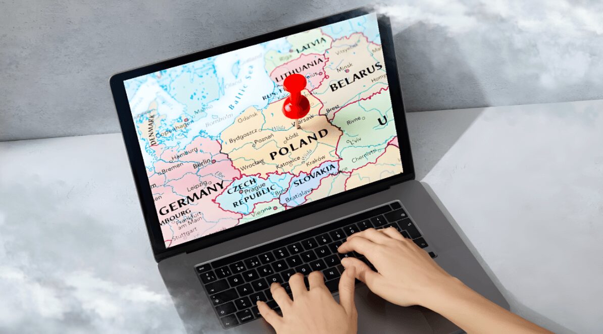 Ilustracja do artykułu: Najlepsze miasto do życia w Polsce. Przedstawia monitor laptopa lezącego na łóżku z mapą Polski. Na klawiaturze widać czyjeś ręce.